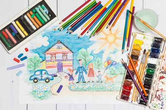 Hand drawn Bright Childrens Sketch With Happy Family, House, Dog, Car on the Lawn with Flowers with lying flat pencils, paints and pastel - concept of children creativity, close up top view