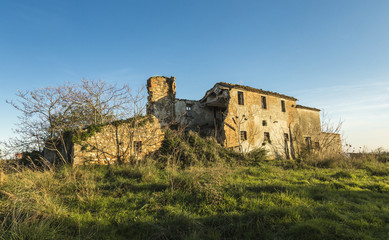 Old abandoned farmhouse in a meadow under blue sky