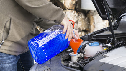 Windshield washer fluid being poured into a vehicle's storage tank