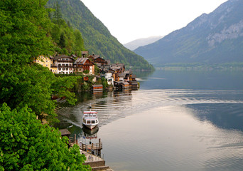 Naklejka premium The Ferry Boat Arriving at the Pier of Hallstatt, an Impressive Lake Village in Austria 