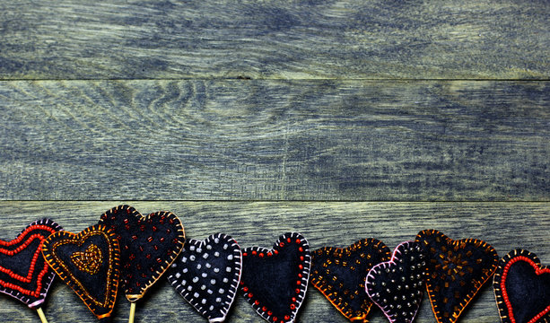 Bottom frame border of Handmade felt hearts on dark old wooden background. Love card for Valentine's day. Concept with big copyspase for hand crafts or DIY illustration.