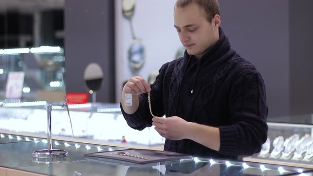 Jewelry shop. Young man chooses a bracelet