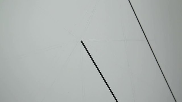 A girl makes a drawing on the wall with a pencil and a ruler. Close-up.