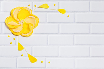 White Brick Background With Handmade Yellow Flower