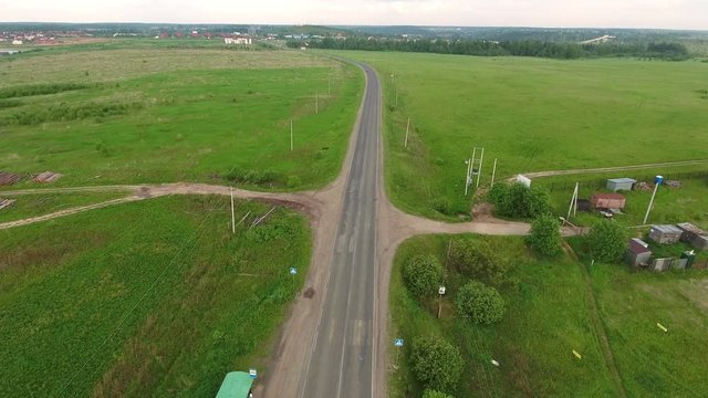 Country road passes through the green meadows in Moscow countryside. Drone flight. Russia
