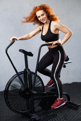 Fototapeta na wymiar Young athletic woman riding the air bike at the gym