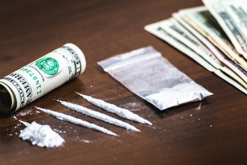 Lines of cocaine and some drugs pill in plastic packet, rolled dollar banknote