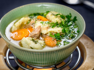 Duck soup with dumplings and carrots on fire heater
