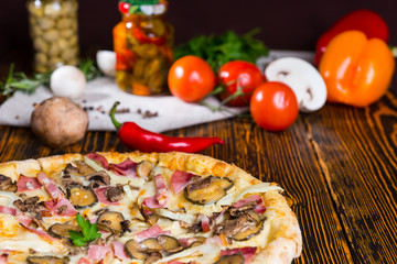 Tasty pizza with pickles on wooden table, tomatoes and other veg