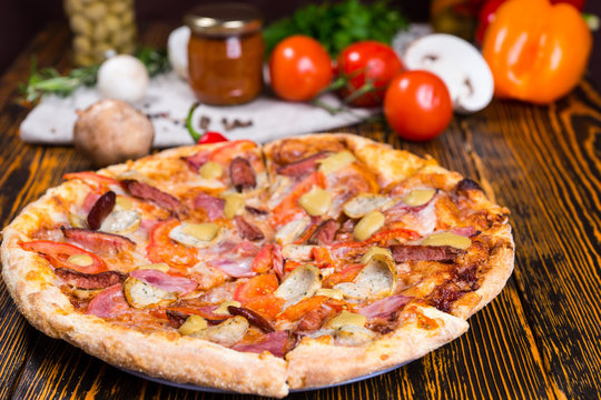 Tasty pizza on wooden table, tomatoes, mushrooms and other veget