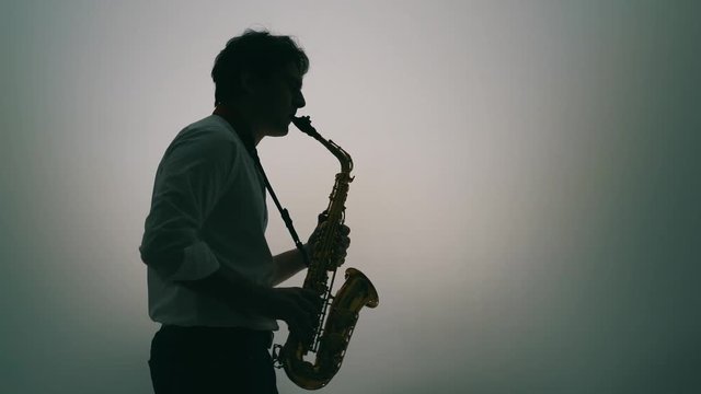 Saxophone player over a light grey background. Real time.