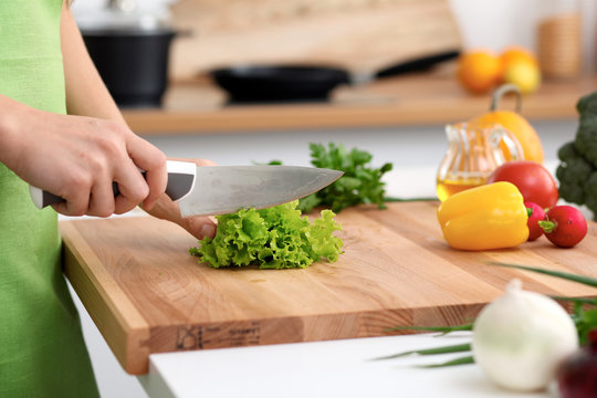 Close up of  woman's hands cooking in the kitchen. Housewife slicing ​​fresh salad. Vegetarian and healthily cooking concept