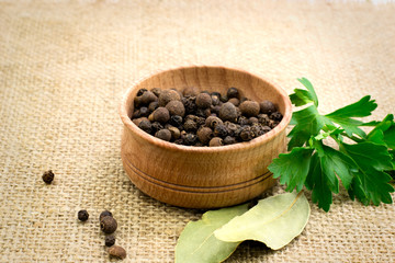 a mixture of peppers in a wooden bowl with parsley and bay leaf