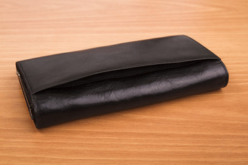 Black leather female purse on wooden background