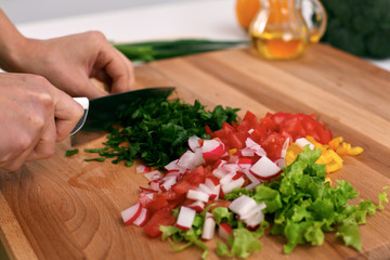 Close up of  woman's hands cooking in the kitchen. Housewife slicing ​​fresh salad. Vegetarian and healthily cooking concept