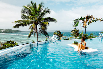 Child relaxing in infinity pool with ocean view