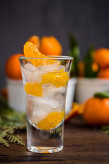 Glass with fresh juicy ripe Mandarins Tangerines, ice. Copy space and Closeup on dark background. Front view