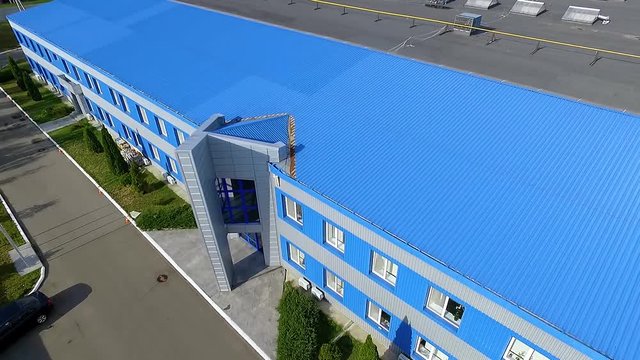 Flight beside warehouse storage building facade exterior HD aerial video: blue commercial industrial architecture building