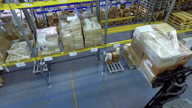 Worker in loader transport loading goods boxes in warehouse storage HD video. Forklift unload pallets with cardboard boxes to shelf. Man working on lift truck