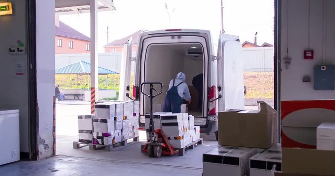 Delivery worker loading cargo van with cardboard boxes in storage warehouse 4k video. Goods transportation and shipping