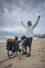 Long Distance Cyclist on Beach with Arms in the Air