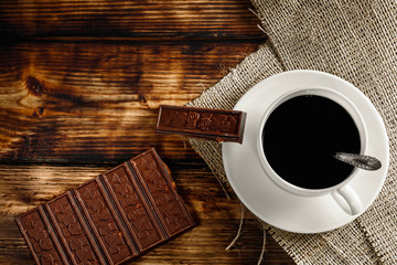 coffee cup and beans, cinnamon sticks, nuts and chocolate on woo