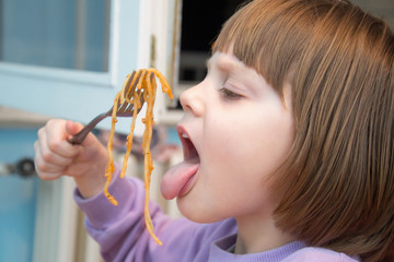 Cute little brown hair girl eating spaghetti 