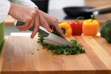 Closeup of human hands cooking vegetables salad in kitchen on the glassr table with reflection. Healthy meal and vegetarian concept