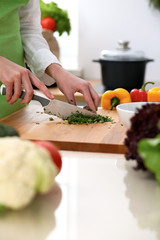 Closeup of human hands cooking vegetables salad in kitchen on the glassr table with reflection. Healthy meal and vegetarian concept