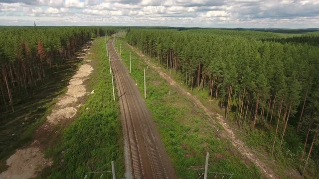Drone flying over empty double line railway in coniferous woods of Karelia, Russia

