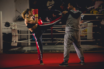 Girl kickboxer sparring with coach