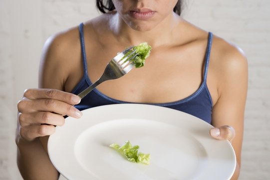 young woman holding dish with ridiculous lettuce as her food symbol of crazy diet nutrition disorder