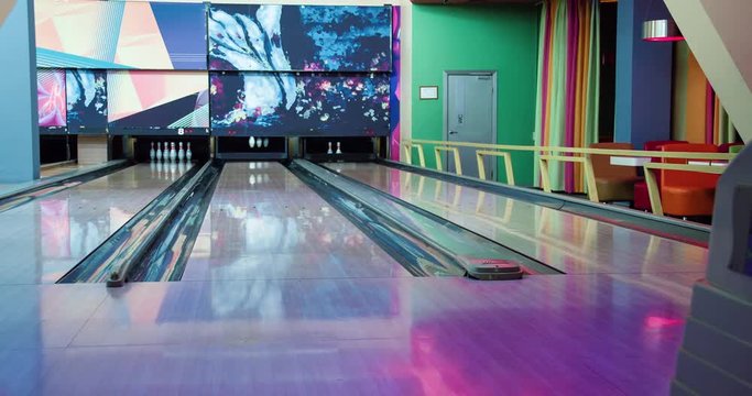 Young man playing bowling game and throwing ball to lane 4k leisure video. Guy rolling ball on alley back view. Hobby and competitions
