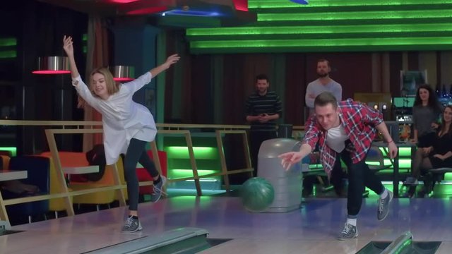 Friends playing and having fun at bowling game HD slow-motion video leisure video. Young man and woman rolling ball throwing to lane. Hobby and competitions