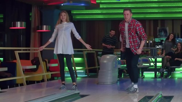 Young friends playing bowling game HD slow-motion video. Man doing good throw, rolls ball and happy for win. Lucky shot hit. Hobby, leisure and competitions