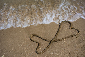 Fototapeta na wymiar Hemp rope is arranged in a heart shape on the beach.