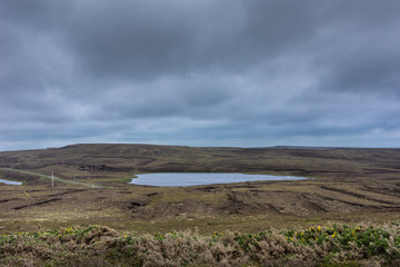 North Coast, Scotland - June 6, 2012: Lake in relative flat waste land behind Dunnet Head lighthouse. Cloudy gray-blue sky. Terrain is rather brown than green. 