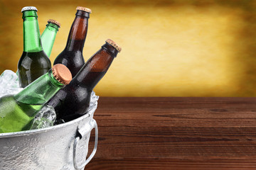 Closeup of a metal ice bucket filled with assorted beer bottles. Horizontal format with copy space and warm background. © Steve Cukrov