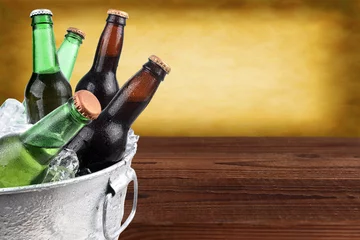 Foto op Aluminium Closeup of a metal ice bucket filled with assorted beer bottles. Horizontal format with copy space and warm background. © Steve Cukrov