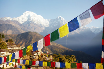 Spectacular view of grand snow capped summits of the Himalayan mountain range rising above in background, with rows of colorful Buddhist prayer flags strung along mountain passes in foreground - obrazy, fototapety, plakaty