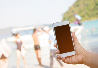hand hold smart phone on blurred beautiful sea blue sky with tra