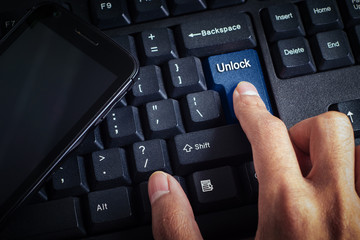 business concept shows the smartphone as well as the fingers that press UNLOCK on the keyboard
