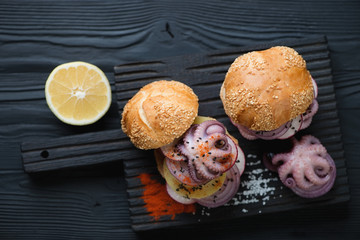 Burgers with pulpo a la gallega over black wooden background