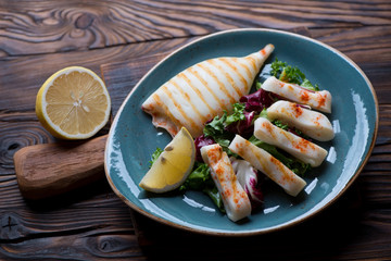 Grilled calamari with fresh salad mix in a rustic wooden setting