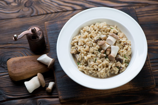 Porcini risotto in a glass plate, rustic wooden setting