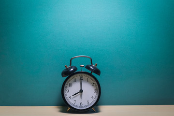 alarm clock on table on mint green and blue background
