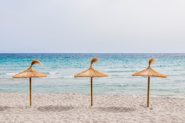 Straw umbrellas on sand beach.