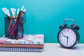 alarm clock,Books and color pens on wooden table with copy space.Green background.