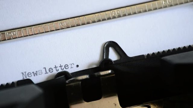 Typing the word Newsletter with an old manual typewriter
