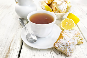 Tea in white cup with lemon cookies on board
